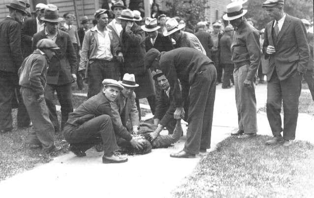 Strike supporter killed by police in Toledo, 1934. 3 comrades squat beside him, as others stand nearby. https://libcom.org/article/toledo-auto-lite-strike-1934-jeremy-brecher