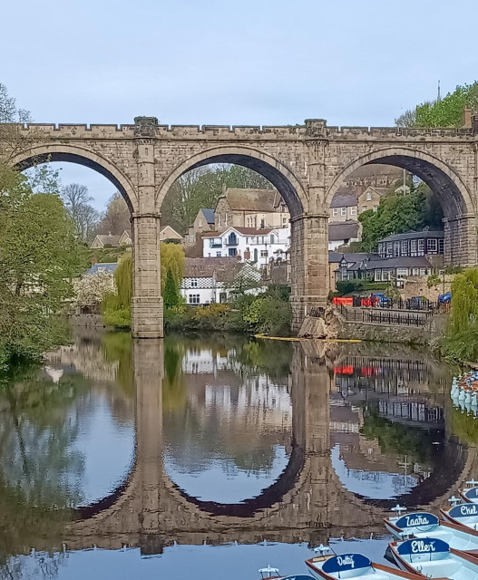 Foreground: river with reflection of viaduct.
Middle: viaduct and buildings.
Top: blue/grey sky.