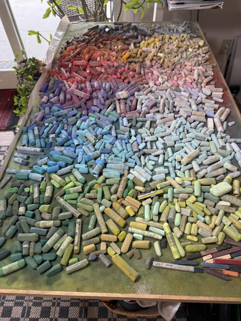 A huge pastel tray table with the sticks organized roughly in a rainbow spectrum. My guess is about a thousand sticks. 
