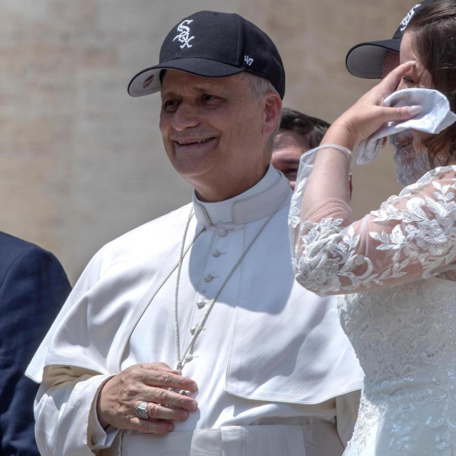 Pope Leo Wearing white vestments and a black White Sox hat.