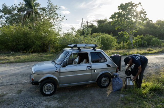 A photo via The Guardian of a guy leaning over to load his small hatchback Fiat with charcoal