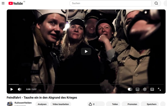 Fünf Personen (Männer und Frauen zwischen zwanzig und vierzig) in Seefahrer-Uniformen, die spannungsvoll und begeistert auf einen Punkt knapp oberhalb dem Betrachter blicken. Es ist ziemlich dunkel. Ein "Play"-Pfeil liegt über dem Bild, das von der Youtube-Website eingerahmt ist.