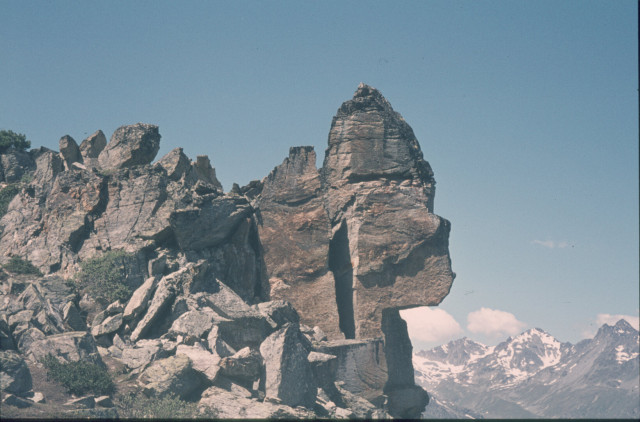 Felsformation mit Spitze, Hintergrund verschneite Berge, blauer Himmel