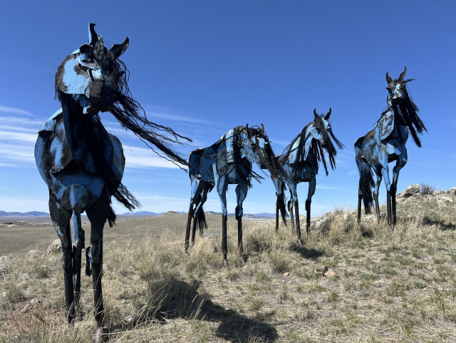 Four horse sculptures standing in a row, with one more prominent on the left.