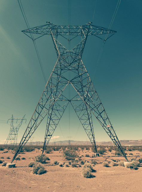 Photo of an electrical transmission line tower in the desert of El Dorado Valley, Nevada. Numerous lines of towers can be seen stretching into the background. This is one tower among thousands that transfer electricity produced at Hoover Dam to Los Angeles. Photo has been processed through a 'Vintage' filter.