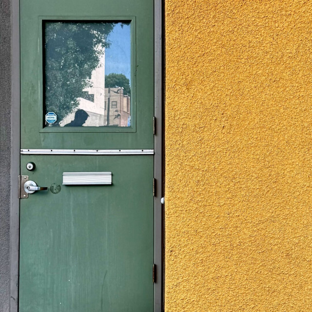 Sage green door next to a yellow/orange wall