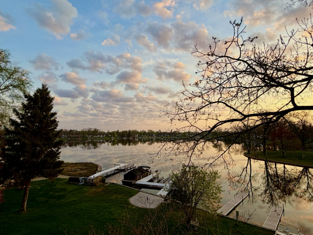 Sunrise photo of puffy clouds over a still lake.