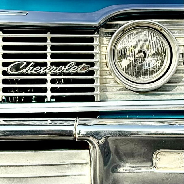Front grill of a teal 1960s-ish Chevrolet Impala.