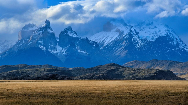 snow covered granite peaks in front of yellow colored grass at the beginning of autumn