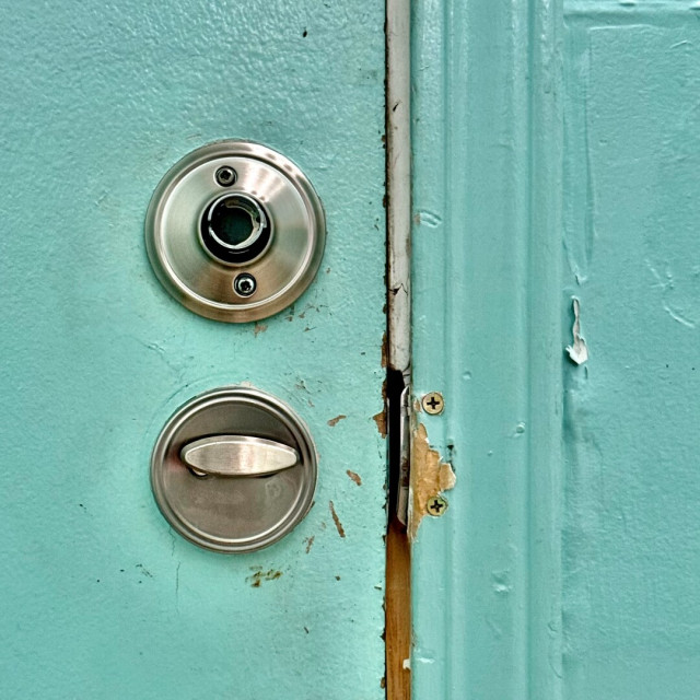 Door inside a public restroom that I only realized had lost its doorknob after the door had closed. The wall is painted mint green and there are signs of past victims desperately trying to escape in the absence of a proper doorknob.