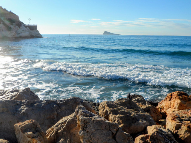 Rotsen, de middelandse zee met kleine golfjes, en verderop het pauweneiland, bij Benidorm in Spanje