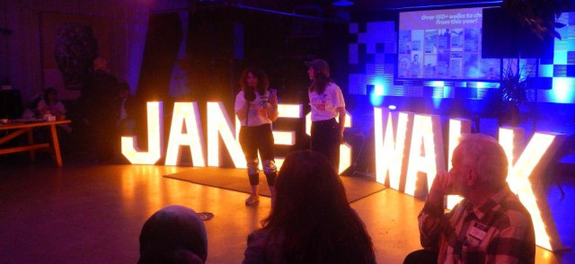 Jane's Walk Festival Organizers wearing Jane's Walk 2026 T-Shirts standing in front of Giant Lit up Letters spelling JANES WALK as they speak to the assembled Walk Leaders
