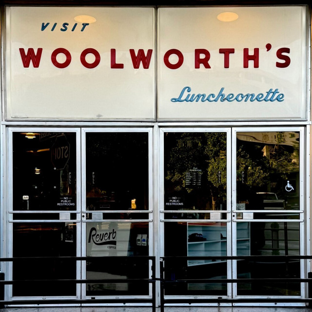 Double double doors with a sign above that says "Visit Woolworth's Luncheonette"