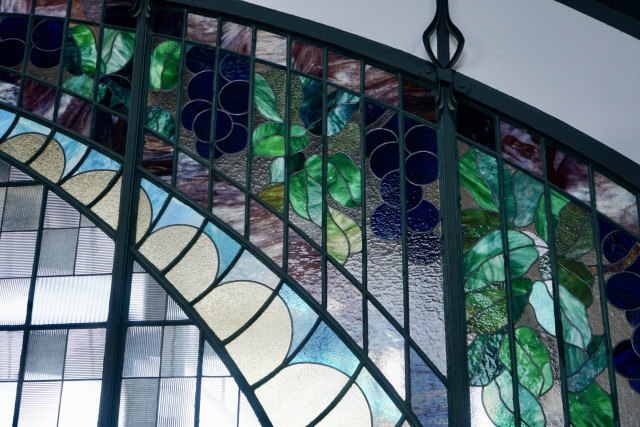 Détail de vitraux à motifs stylisés représentant semble-t-il des feuilles et du raisin.