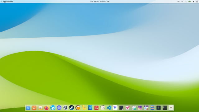 A screenshot of elementary OS desktop in light mode. It shows the desktop is using a bliss style wallpaper depicting blue sky and green hill. There is a top panel that shows the menu button on the left, the clock on the center, and system tray icons on the right. The bottom of the desktop has a dock that is full of app icons.