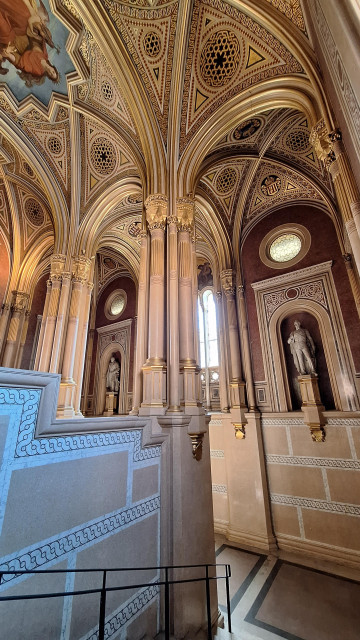A wide angle shot of a grandiose staircase, marble and gilded stucco.