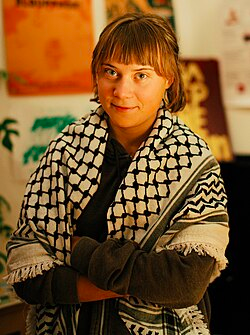 Portrait photo of Greta Thunberg with a keffiyeh scarf around her shoulders, taken from the Wikipepedia entry
