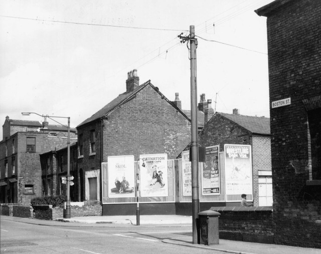 b/w street photo including film poster for: Blue Hawaii / Tom Thumb / Mysterious Island / The Pirates of Blood River  