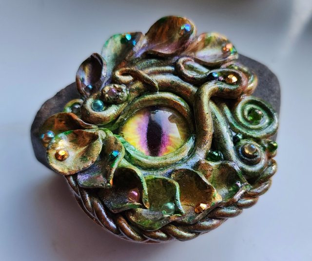 A green-bronze dragon eye with a yellow and purple iris.