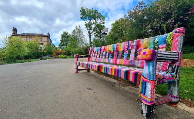 A colourful knitted and crocheted cover on a bench in Glasgow's Botanic gardens.