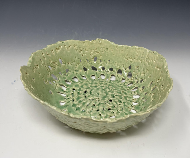 Top-down view of a bowl made from a round crocheted fabric, soaked in Laguna's B-Mix slip, then placed on a slump mold until it was stiff enough to remove. After bisque firing (at this stage the piece is super fragile), I mouth-sprayed several layers of Korean Celadon glaze. It's in one piece -- so that's something. 