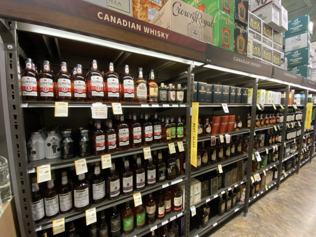 A long aisle, with multiple shelves labeled “Canadian Whisky”, all full!
