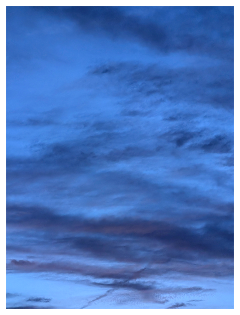a sky at dusk filled with layered clouds in shades of deep blue and soft purple, with hints of pink near the horizon.