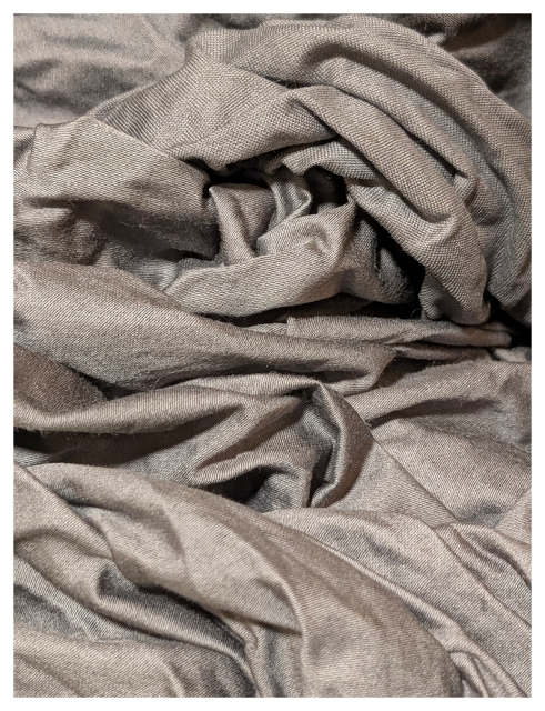 close-up view of soft, gray fabric with a slightly shiny texture, shown in rumpled, layered folds and creases.