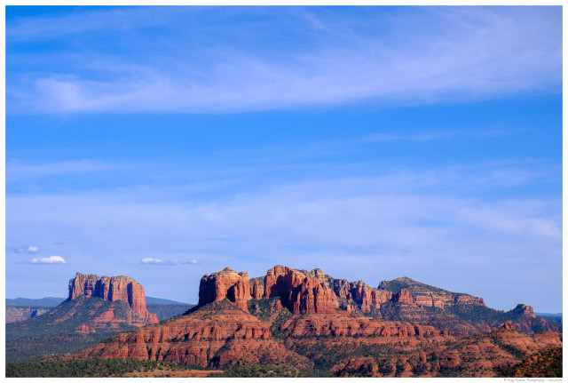 Panoramic view of Sedona's red rock formations under a vivid blue sky with wispy clouds, seen from Schuerman Mountain, Arizona.