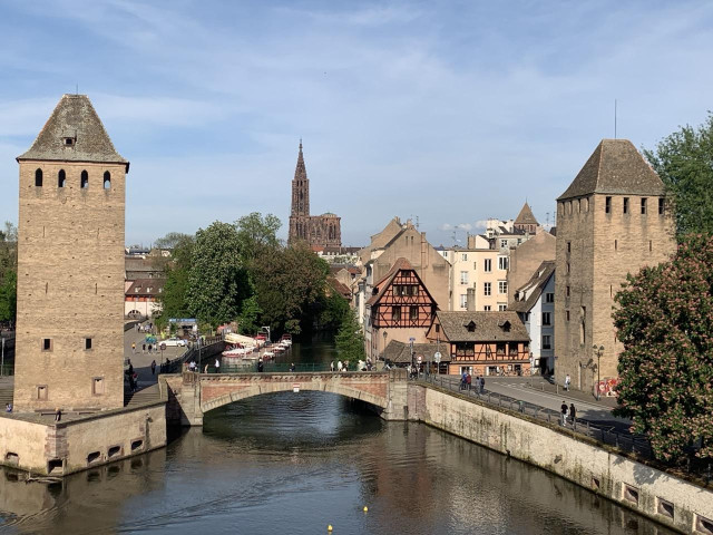 Un petit pont ancien à Strasbourg, entouré de deux tours avec le centre ville au fond où il y a la cathédrale.