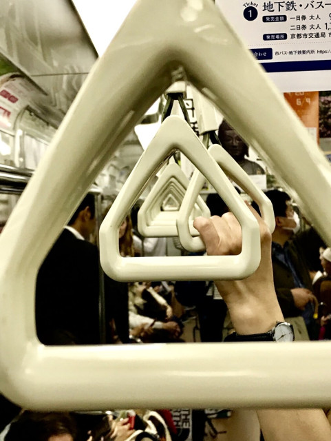 A shot through hanging hand grips on a commuter train. One grip is being used.