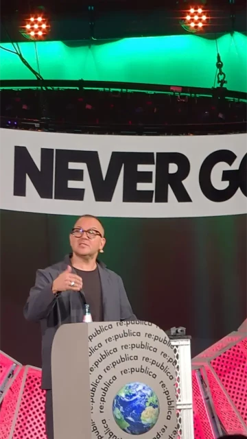 Doctorow on stage of #republica. In big lettering: "NEVER" (give you up) above.