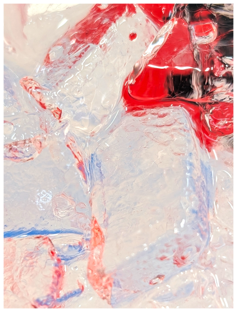 close-up view of irregularly-shaped ice cubes with red and blue liquid reflections. the ice appears translucent with textured surfaces, while the red and blue colors create abstract patterns across the image.