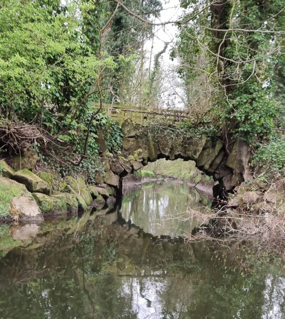 Taken from a boat on the Ure at Newby Hall, an arched bridge over a tributory where a footpath follows the river on the far bank. 
