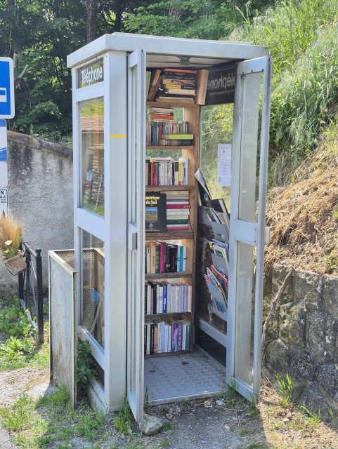 An old Public phone kiosk in a village in France, converted into a free lending library