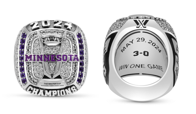 A polished championship ring shown from two angles against a light gray background.

On the left, the front of the ring features large silver “2024” lettering across the top and “CHAMPIONS” across the bottom. The center displays the Professional Women’s Hockey League Walter Cup surrounded by dense clear stones, with a purple “MINNESOTA” banner running across the middle. Vertical rows of purple gemstones line both sides of the face.

On the right, the inside of the ring is shown. Engraved text reads “MAY 29, 2024” in an arc above a bold “3-0,” with the phrase “WIN ONE GAME” beneath it. Black enamel accents and additional clear stones decorate the shoulders and edges of the ring.