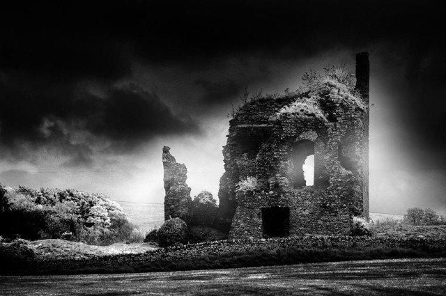 Atmospheric black and white photo of a ruined castle under a dark sky.