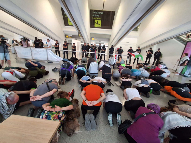 A group of protesters kneel with their hands behind their backs and their heads on the floor, adopting the stress positions forced upon the flotilla crew during their illegal abduction.