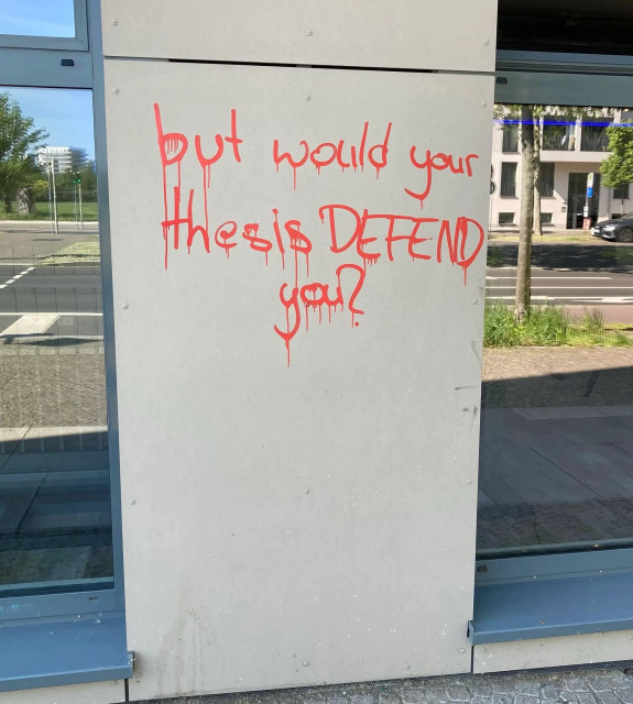 Graffiti on a concrete wall, in orange spray paint that's dripping:

but would your thesis DEFEND you?