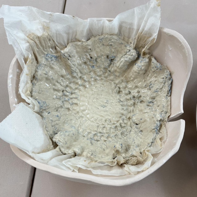 The crocheted round thing was soaked in B-Mix slip for about an hour before shaking off the excess slip and placing it in a slump mold lined with paper towels. The towels soaked up some of the excess moisture from the slip. [Note: the slump mold was a failed bowl that I made and repurposed.]