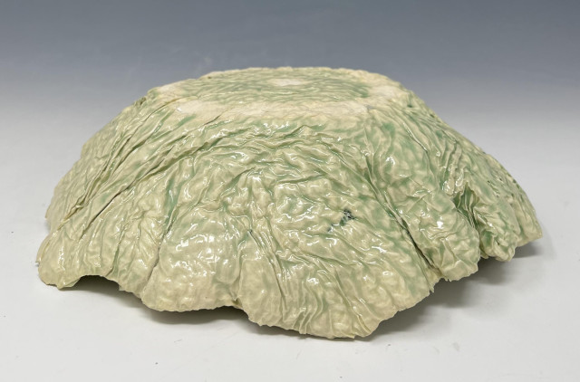 Crocheted-ceramic bowl dipped once in Korean Celadon glaze, positioned upside-down. It shows off the texture of the crocheted fabric and crinkled paper towels nicely.