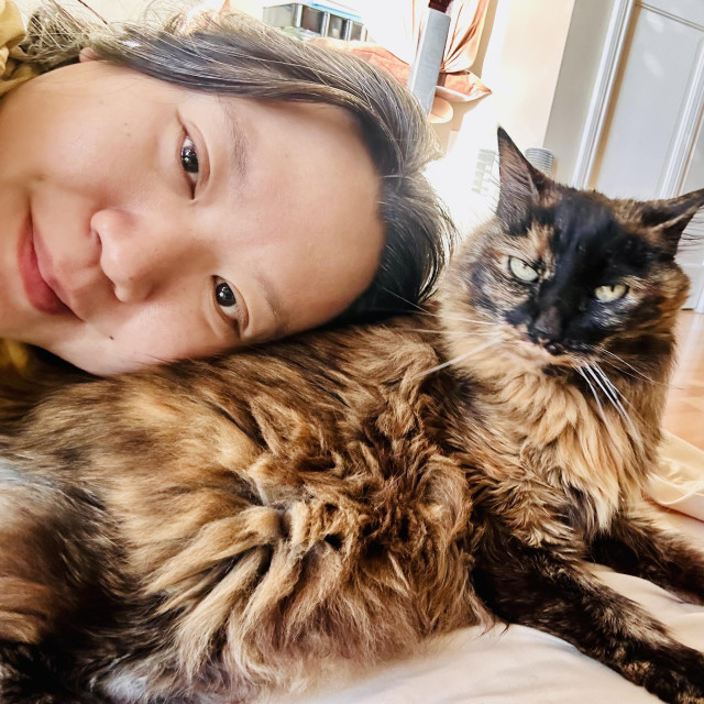 Selfie of me with my head on the butt of a large and gorgeous tortie cat 