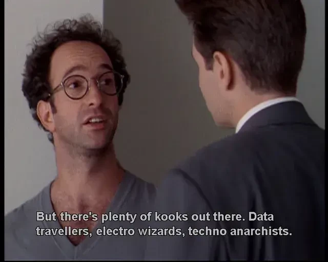 Image from The X-Files, with Mulder on the right facing a man with dark curly hair, glasses and grey T-shirt who says, 'But there's plenty of kooks out there. Data travellers, electro wizards, techno anarchists.'