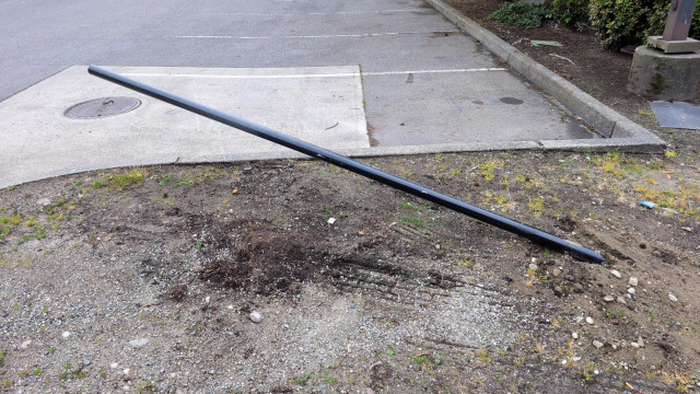 A knocked-over pole in a Lowe's parking lot that used to be a Flock camera.