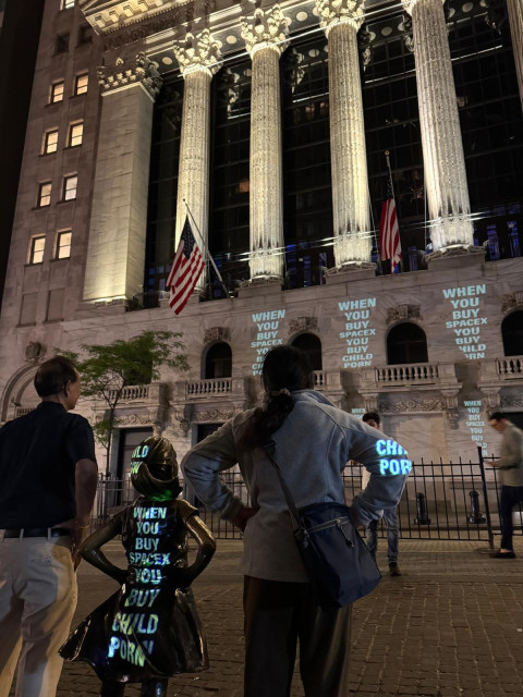 someone has made multiple projections of the phrase "when you buy spacex you buy child porn" onto the NY Stock Exchange building