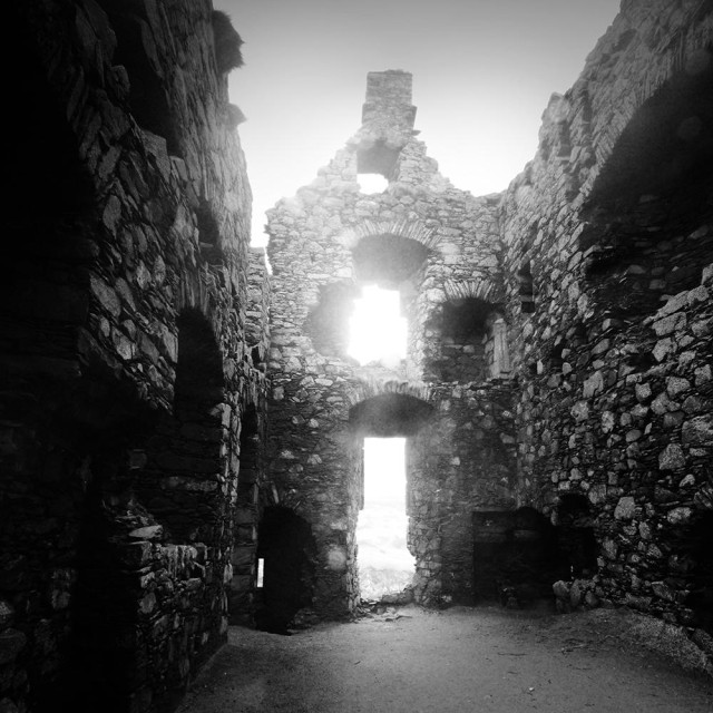 Atmospheric black and white photo of the interior showing the crumbling walls of a ruined castle.