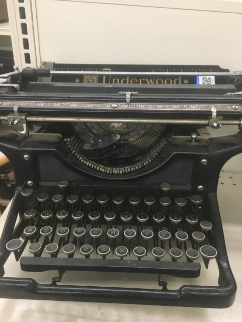 A black Underwood typewriter, missing a foot but otherwise still good. Two empty ink reels sit inside of it.