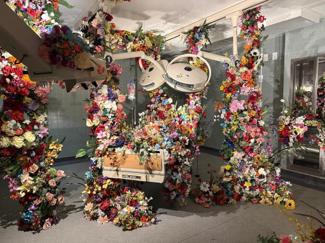 a hospital room installation transformed by lush installations of flowers
