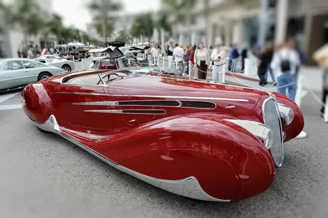 A streamlined incredibly long futuristic art deco car in deep ruby red