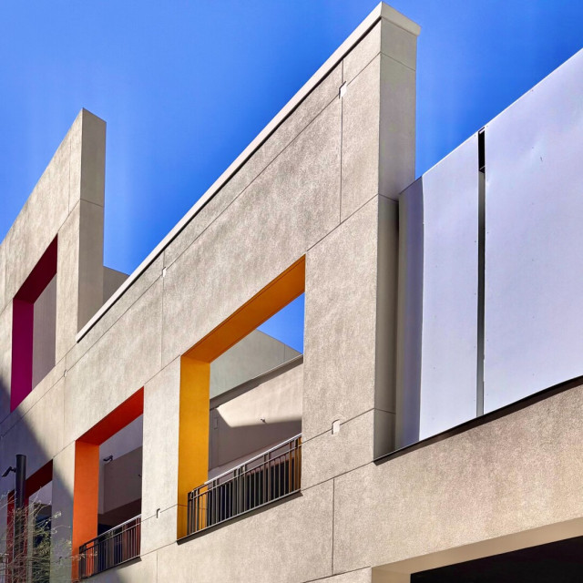 Decorative wall with cutouts kind of implying windows. The insides are painted with bright colors like yellow, orange, and magenta